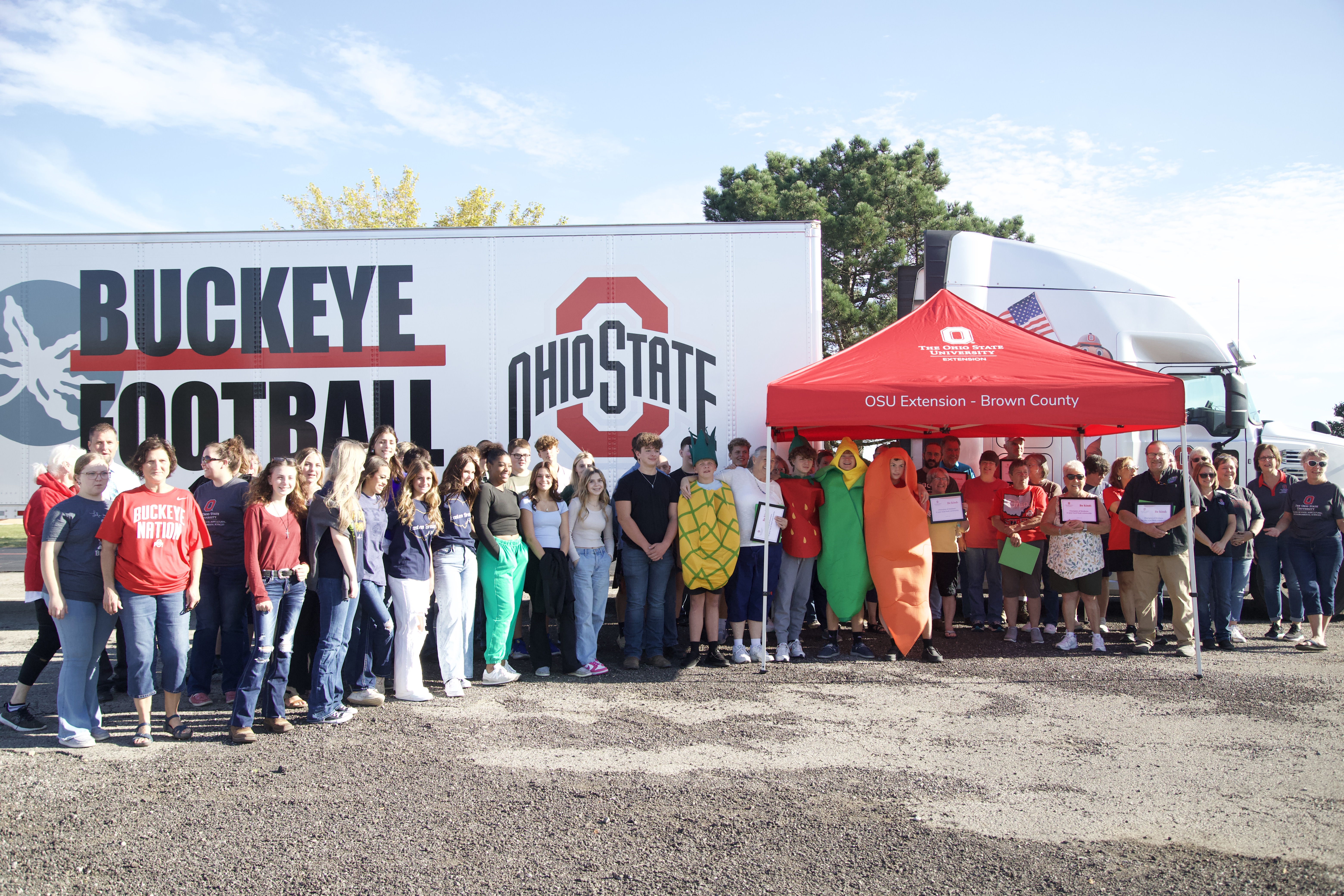 volunteers pose in front of football equipment truck