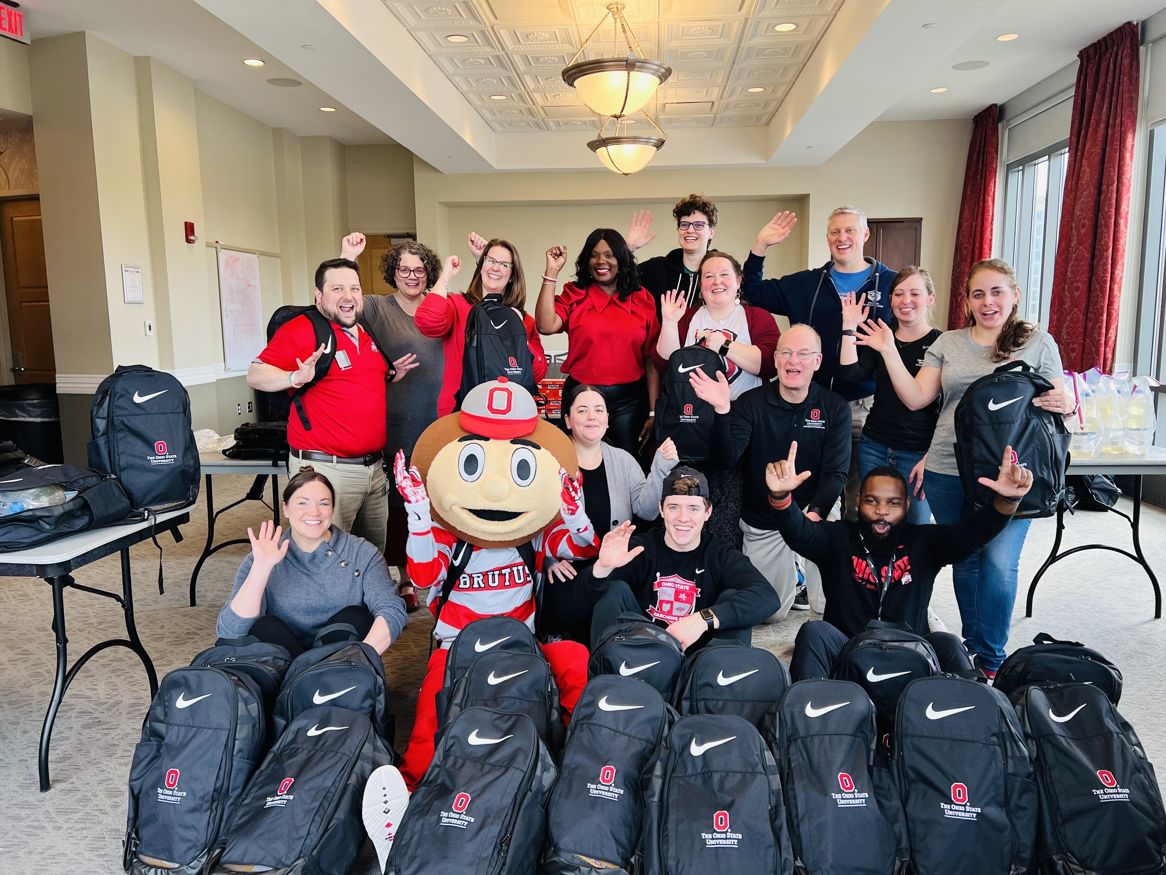 A group of people pose with backpacks made for underprivileged children.